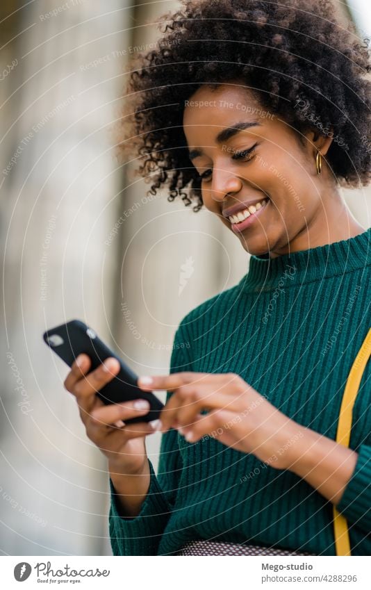 Geschäftsfrau, die ihr Mobiltelefon im Freien benutzt. Afro-Look Business Frau Mobile Telefon schwarz modern Stil brünett Apparatur positiv Konzept Anschluss