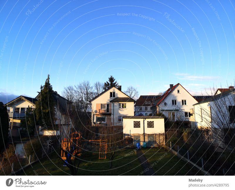 Typische Wohnhäuser mit Spitzgiebel als Eigenheim im Licht der untergehenden Sonne vor strahlend blauem Himmel in der hessischen Provinz in Wettenberg Krofdorf-Gleiberg bei Gießen in Mittelhessen