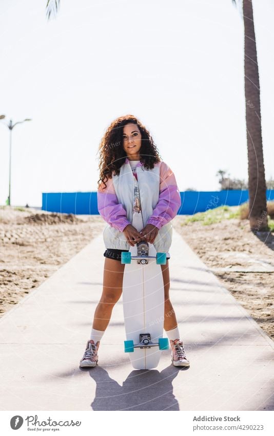 Frau mit Skateboard auf einer Böschung stehend Skateboarderin Hobby Strand Küste Sport Stauanlage Strandpromenade Bürgersteig Longboard lässig sportlich jung