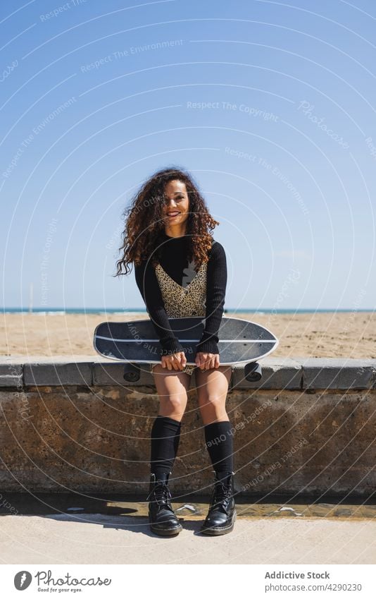 Stilvolle Frau mit Skateboard am Strand Skateboarderin Hobby Küste Sport Strandpromenade Stauanlage Borte Longboard lässig sportlich jung Übung üben Lifestyle