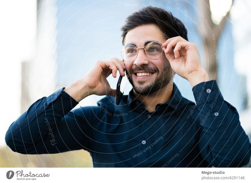 Junger Mann beim Telefonieren im Freien. jung Mobile urban Lächeln Anschluss Apparatur Porträt positiv Drahtlos Beteiligung laufen Blick Tippen sprechend reden