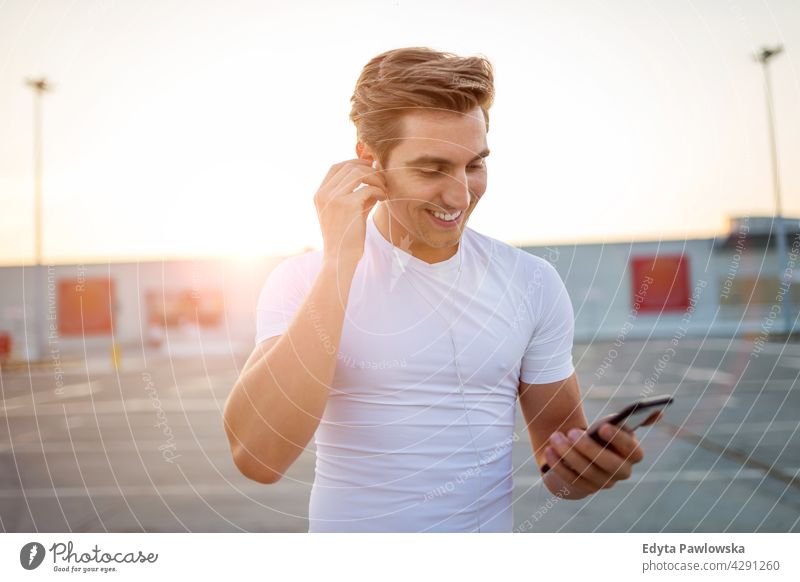 Junger Mann überprüft sein Smartphone vor dem Training MP3-Player Musik hören Kopfhörer App Radio Monitor Verlauf Handy Technik & Technologie Jogger Läufer