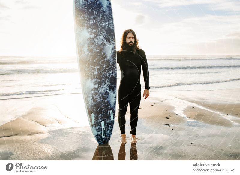 Surfer stehend am Strand mit Surfbrett Mann Natur Sonnenuntergang winken im Freien Neoprenanzug Meeresküste männlich Brandung Sportler MEER Vollbart Surfen