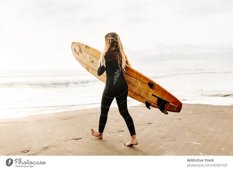 Weiblicher Surfer am Strand mit Surfbrett Frau Natur Sonnenuntergang winken im Freien Neoprenanzug Meeresküste Brandung Sportlerin MEER Surfen Spaziergang Hobby