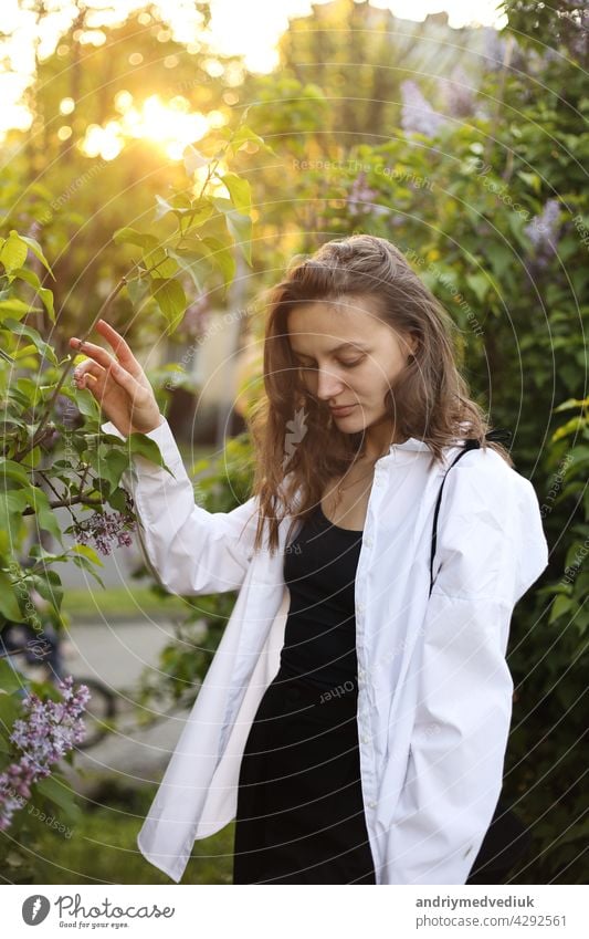 unwirklich schöne junge Frau zu Fuß in einem grünen blühte im Frühjahr in einem Lavendelgarten mit einem Blumenstrauß von Flieder in den Händen. Closeup Mode romantisches Porträt. riechen die Blumen