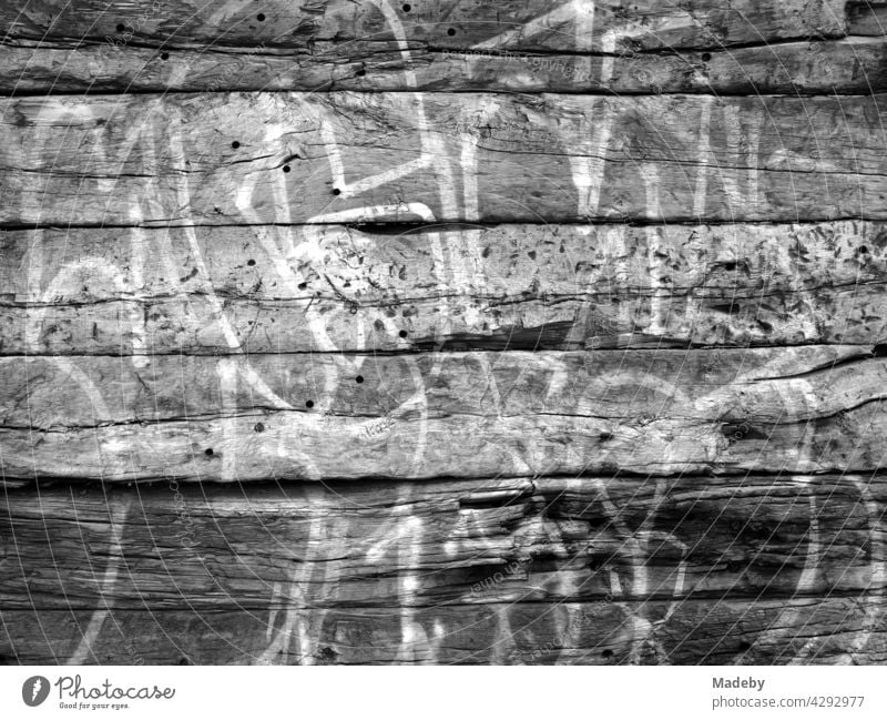 Weiße Konturen großer Buchstaben als Graffiti auf einer alten Hauswand am alten Hafen in Offenbach am Main in Hessen, fotografiert in klassischem Schwarzweiß