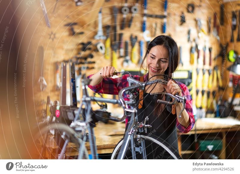 Junge Frau arbeitet in einer Fahrradwerkstatt Vertriebsmitarbeiter Fahrradmechaniker Radfahren Fahrradladen Business Einzelhandel Zyklus hilfreich