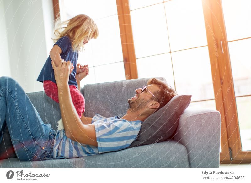 Glücklicher Vater spielt mit Tochter auf Sofa zu Hause heimwärts Mann Papa Familie Eltern Verwandte Kind Mädchen kleines Mädchen Kinder Partnerschaft