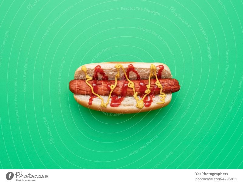 Hot Dog Draufsicht minimalistisch auf einem grünen Hintergrund. oben Amerikaner Brot Brötchen Kalorien Farbe Textfreiraum Küche ausschneiden lecker Hund essen