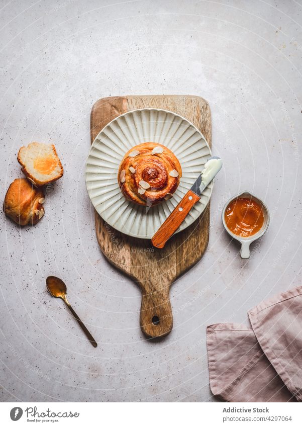 Teller mit Zimtschnecke bei Marmelade Brötchen Dessert dienen Messer Sahne Schneidebrett Serviette Frühstück lecker frisch Lebensmittel Schalen & Schüsseln