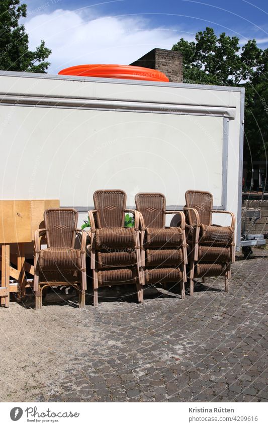 gestapelte stühle stehen hinter einem ausschankwagen korbstühle bierwagen terrasse biergarten gastronomie kneipe draußen beachbar strandbar sand geschlossen