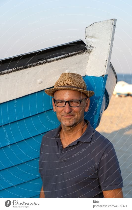 Mann am Boot blau Portrait Fischerei Fischerboot maritim Fischkutter Schiff Farbfoto Meer Strand