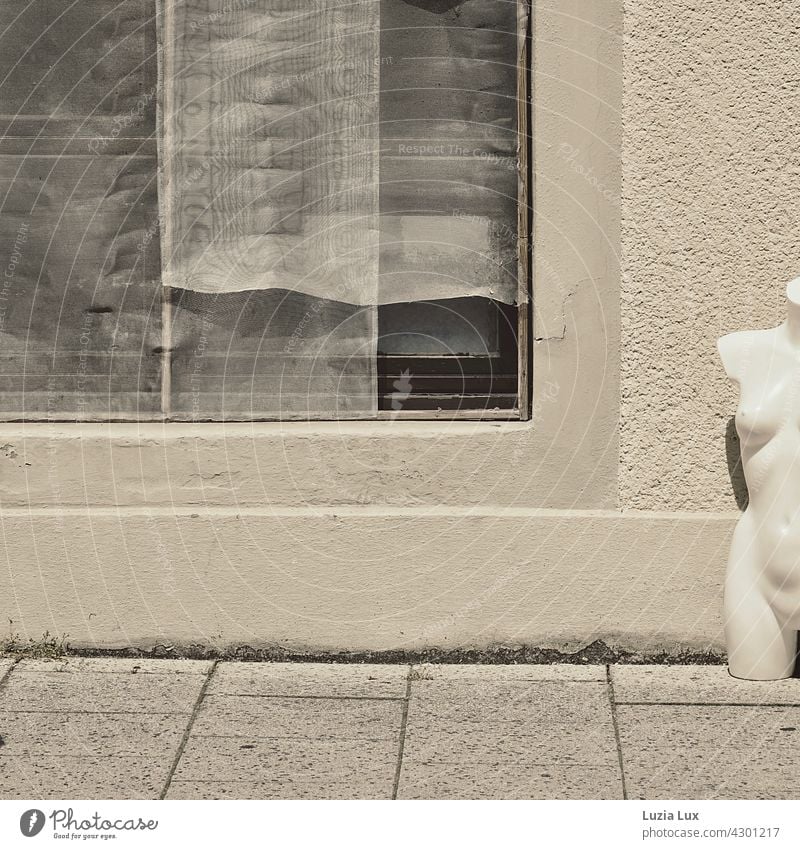 übrig und nackt... Torso einer Schaufensterpuppe steht neben einem leeren Schaufenster mit heruntergelassenen Gardinen Straße Bürgersteig Außenaufnahme Fassade