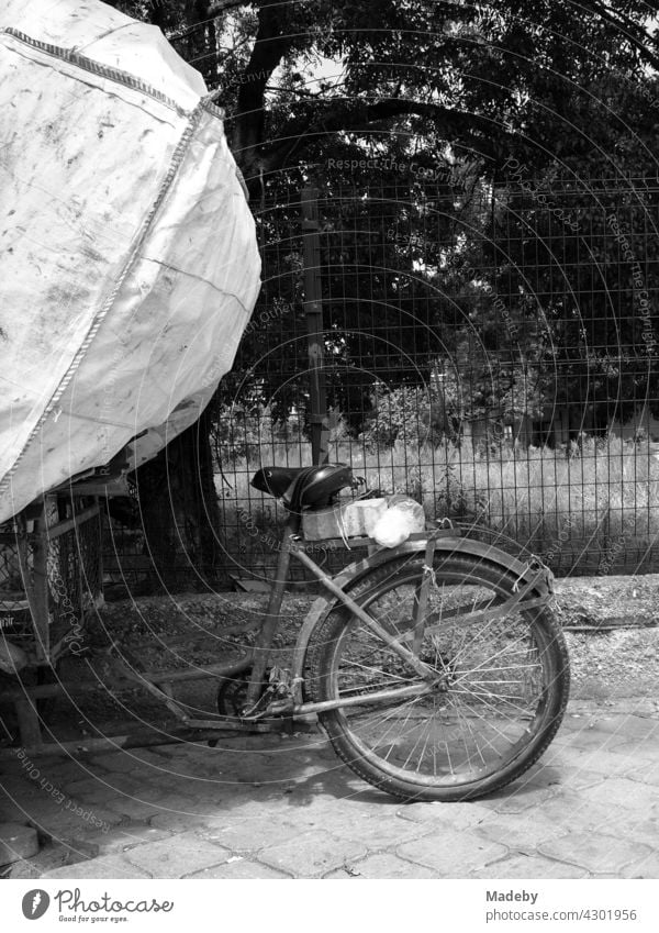 Altes Lastenrad mit riesigem Müllsack im Sommer bei Sonnenschein am Straßenrand in Adapazari in der Provinz Sakarya in der Türkei, fotografiert in neorealistischem Schwarzweiß