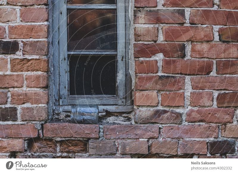 Ein Glasfenster auf alter roter Backsteinwand. Vintage-Fenster in weißem Holzrahmen auf roter Backsteinmauer des Industriegebäudes. Glas auf der Fensterbank liegend.