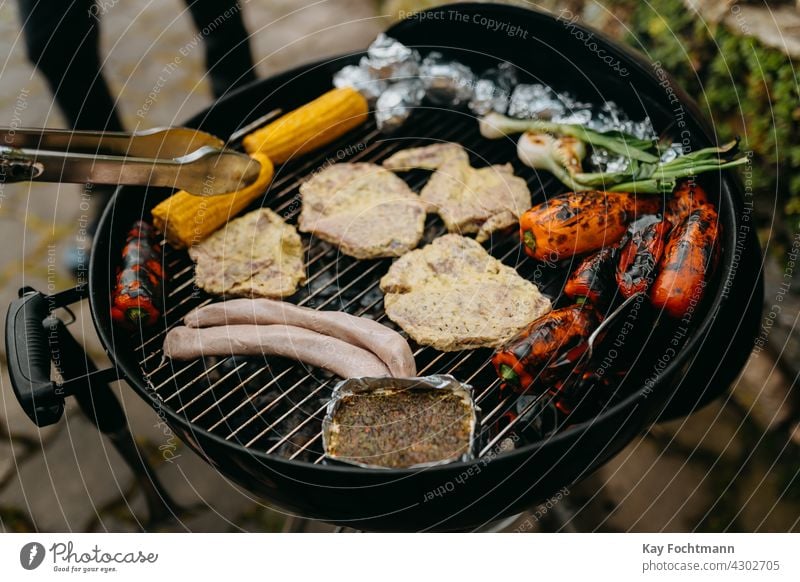 Grillen mit Fleisch und Gemüse beim Barbecue Hinterhof Grillzange Paprika Käse Essen zubereiten Kochaktion Mais Maiskolben Tag lecker Feuer Lebensmittel