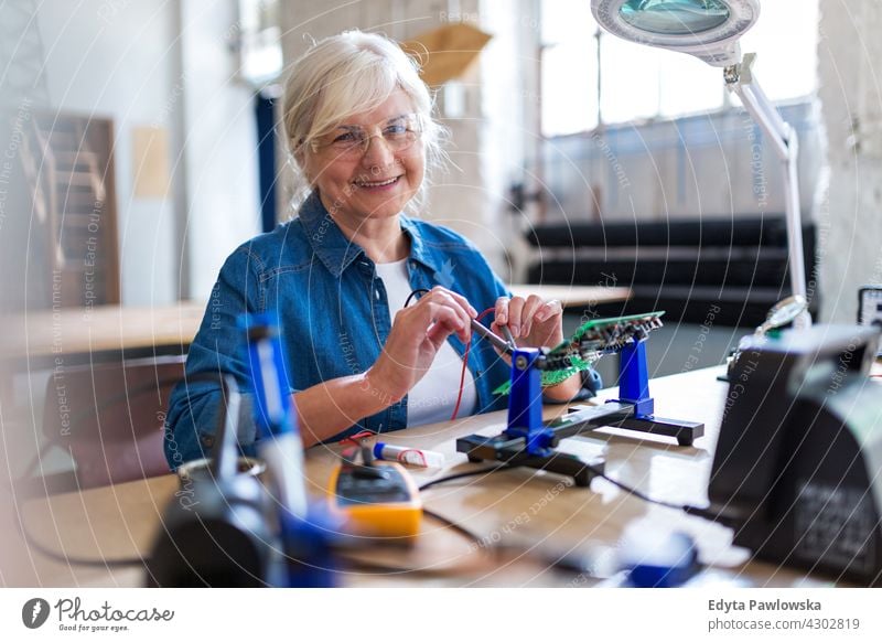 Seniorin in der Elektronikwerkstatt Messung aktuell Elektrizität Elektromonteur Ingenieur Gerät Kompetenz Industrie Job Reparatur Lötkolben löten