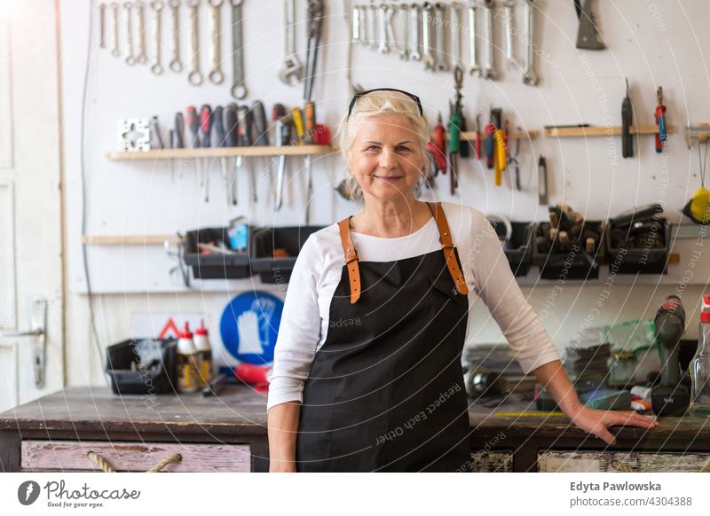 Ältere Handwerkerin in ihrer Werkstatt im Innenbereich Frau Mechaniker Besitzer Beruf Dienst Kleinunternehmen Mitarbeiter arbeiten Techniker Arbeitsplatz