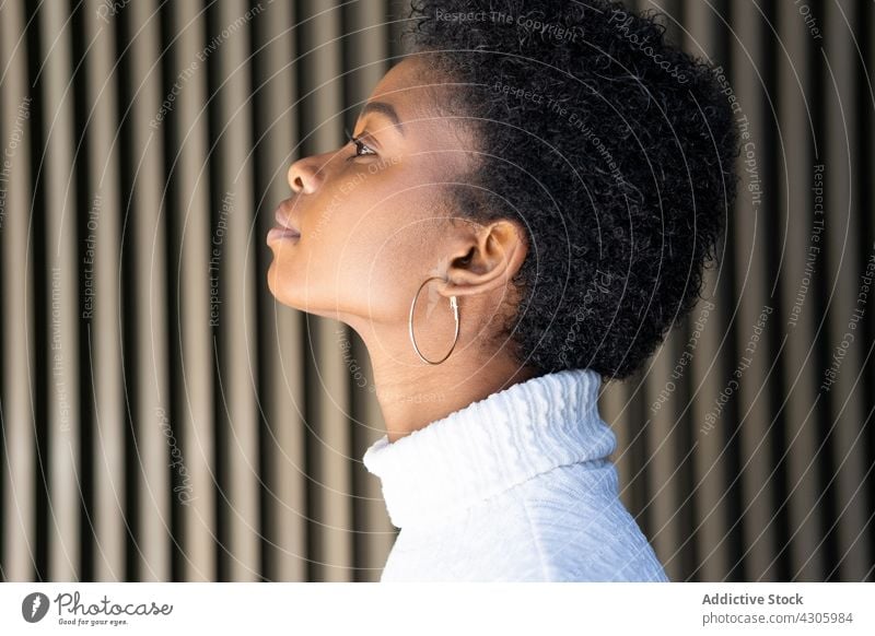 Junge Afroamerikanerin in der Nähe einer gestreiften Hauswand Frau Lächeln Glück Stil urban Straße Großstadt Outfit Mode schwarz ethnisch jung Ohrringe