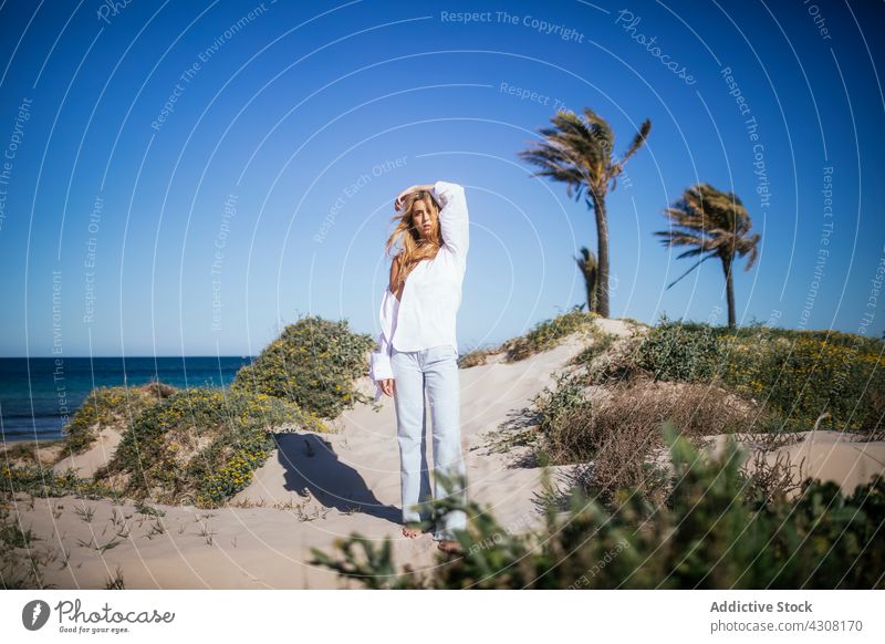 Junge Frau steht am Strand an einem sonnigen Tag Bräune Menschen heiter Sonnenbräune Körper Urlaub blond schön Meer jung MEER Wasser Spaß entspannend Accessoire