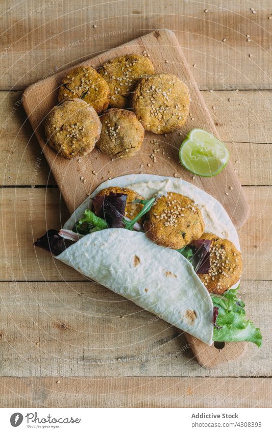 Tortilla mit Falafel und Salat auf Schneidebrett umhüllen Kalk Tisch Küche Süßkartoffel Tradition Lebensmittel Mahlzeit lecker geschmackvoll Speise frisch