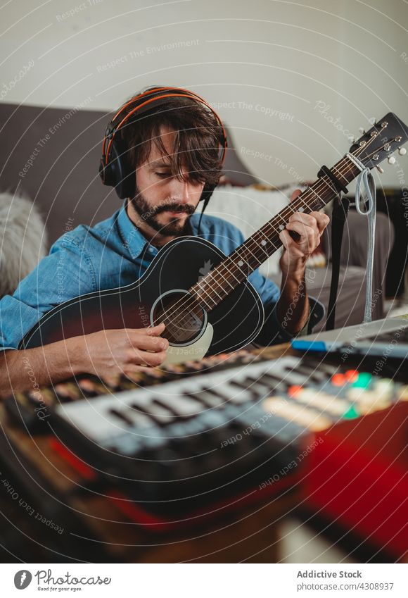 Musiker spielt auf der Gitarre in der Nähe des Laptops zu Hause heimwärts Spielen Kopfhörer Mann jung Tisch Synthesizer Atelier Gerät Apparatur Instrument