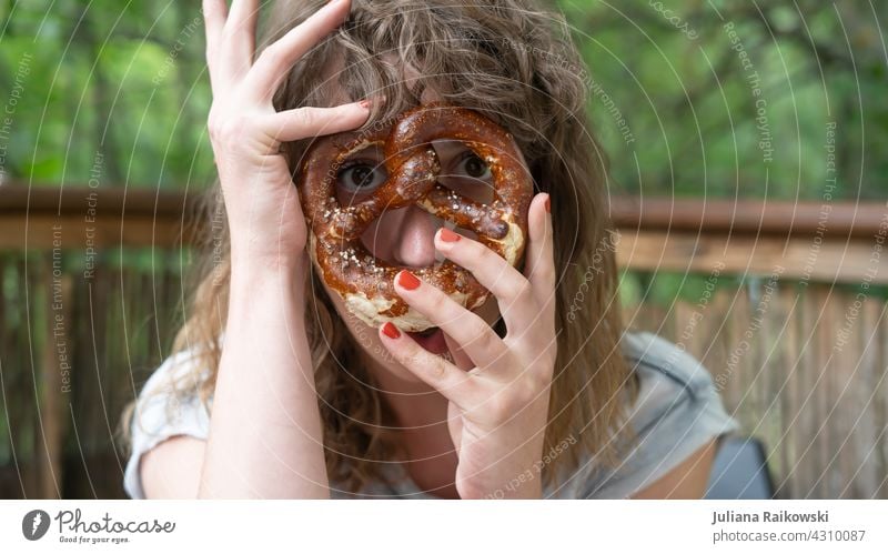 Frau mit Breze vorm Gesicht Brezel Backwaren lecker Bayern Oktoberfest Lebensmittel Teigwaren bayerisch Ernährung Frühstück Farbfoto Snack Vesper Essen salzig