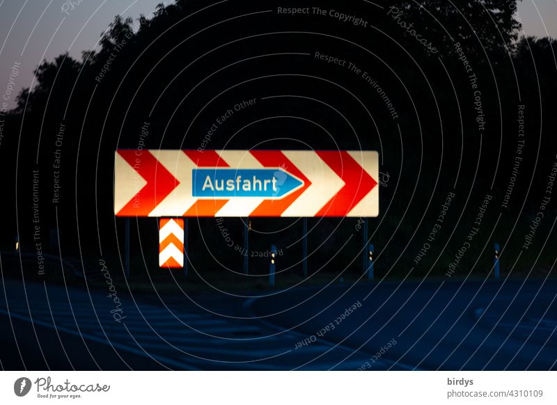 Angestrahltes, auffälliges Ausfahrt - Schild auf der Autobahn. Nachtaufnahme mit richtungsweisendem Verkehrsschild Autobahnausfahrt angestrahlt Pfeil