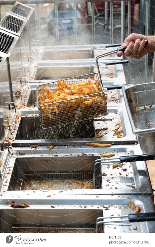 frische Pommes Frites  werden auf einem Festival aus einer Fritteuse genommen Pommes frites Zubereitung Feiern Kartoffeln Marktplatz Fett lecker Ernährung