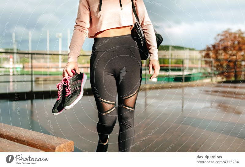 Unbekannte Sportlerin mit Sporttasche und Sportschuhen auf dem Weg zum Training unkenntlich Athlet Mittelteil Top Beteiligung Turnschuh laufen nasser Boden