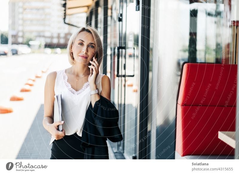 Eine schöne Geschäftsfrau, die in der Stadt telefoniert und einen Ordner mit Dokumenten hält Telefon Frau Straße Business Porträt sprechend Stehen Mädchen