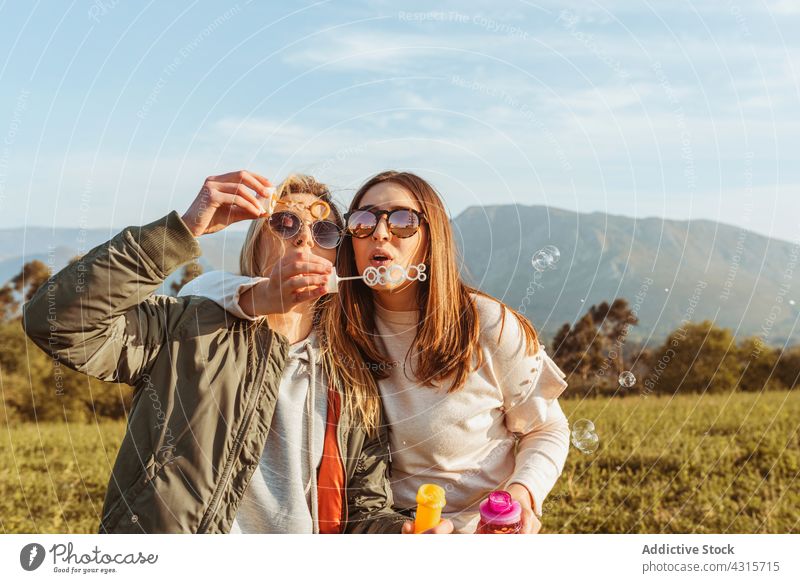 Glückliche Frauen mit Seifenblasen in der Natur Spaß Schlag Zusammensein bester Freund Freundschaft Sommer Sonnenbrille Wiese ruhen Freizeit sorgenfrei Freundin