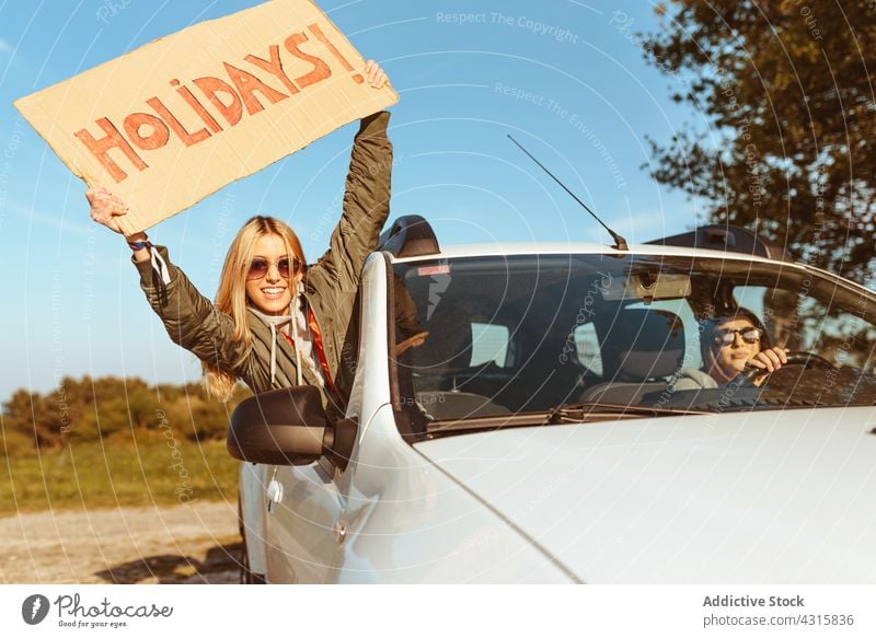 Frauen mit Schild Feiertage fahren im Auto Freundin PKW Spaß Autoreise Zusammensein Glück heiter Fenster Freiheit ruhen genießen Urlaub Reise Ausflug Fahrzeug