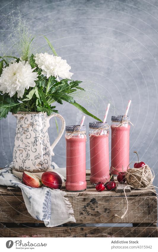 Frischer Fruchtmilchshake in Gläsern auf dem Tisch Milchshake Nektarine Glas trinken dienen Sommer Erfrischung lecker Getränk Blume Vase rustikal Stil süß kalt