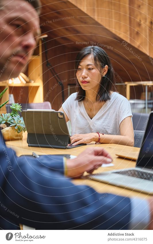 Asiatisches Mädchen arbeitet an ihrem Laptop im Büro mit anderen Cowokern Frau Mann Coworking Smartphone Computer Internet Menschen Tisch Arbeit Schreibtisch