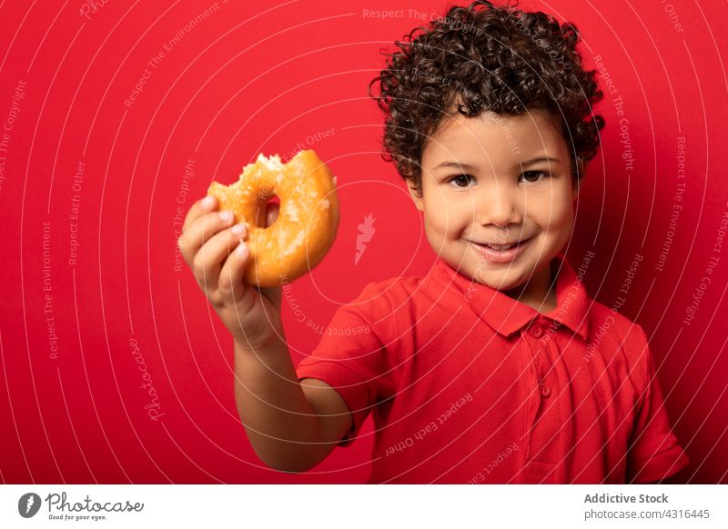 Süßer Junge isst Donut im Studio Kind Krapfen essen Doughnut süß geschmackvoll Dessert Leckerbissen lecker Lebensmittel hungrig Kindheit niedlich Gebäck