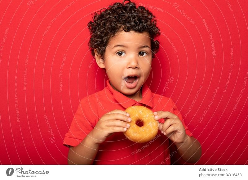 Süßer Junge isst Donut im Studio Kind Krapfen essen Doughnut süß geschmackvoll Dessert Leckerbissen lecker Lebensmittel hungrig Kindheit niedlich Gebäck