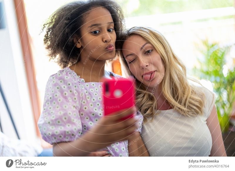 Mutter und ihre junge Tochter nehmen ein Selfie zu Hause Kind Familie multiethnisch gemischte Rassenfamilie vielfältige Familie Vielfalt Afro-Look heimwärts