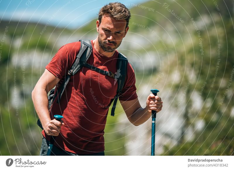 Männlicher Wanderer mit Trekkingstöcken in bergigem Terrain Tourist Wanderung Mast Hochland Rucksack Felsen Tourismus Natur Reisender reisen Abenteuer erkunden