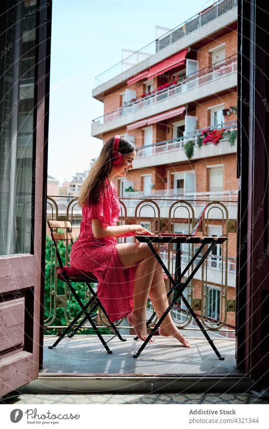 Frau mit Kopfhörern arbeitet auf dem Balkon am Laptop Arbeit freiberuflich Tippen abgelegen Projekt benutzend Terrasse Netbook Apparatur Gerät Internet Browsen