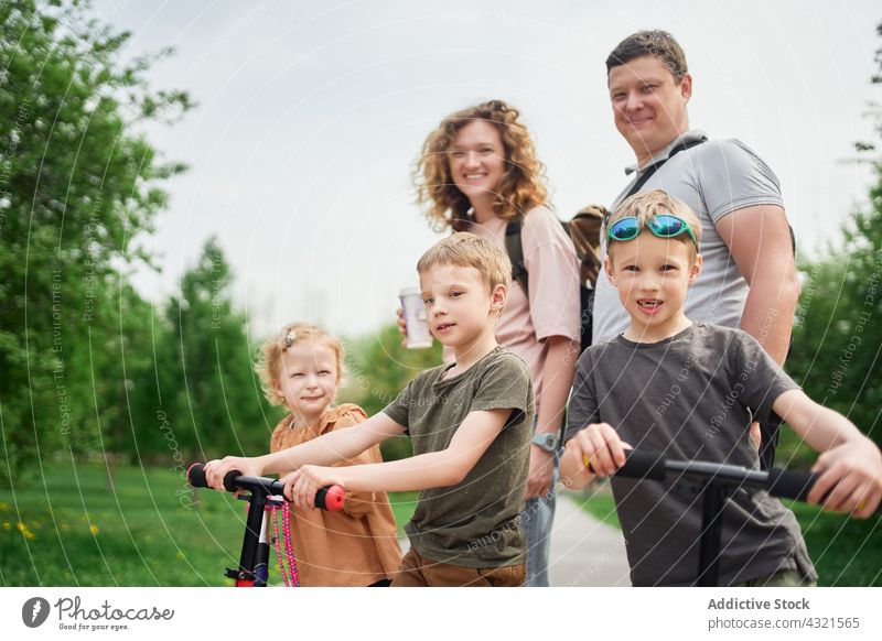 Fröhliche Familie, die gemeinsam im Park Spaß hat Tretroller Kinder Wochenende Vergnügen unterhalten Zusammensein heiter Paar Liebe Partnerschaft Bonden Glück