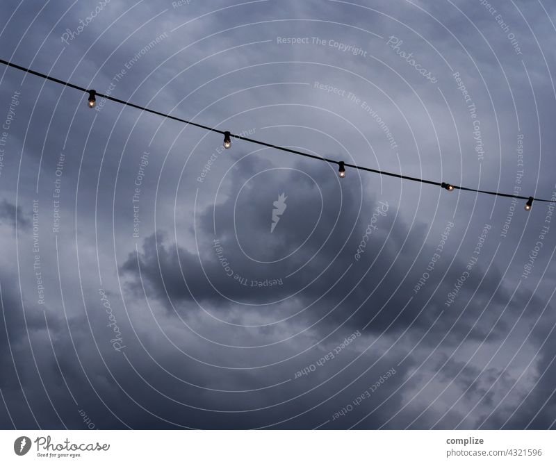 Lichterkette vor dunkelen Gewitterwolken Unwetter Starkregen Unheil Gastronomie Biergarten pandemie Wolken Wetter Klima Klimawandel