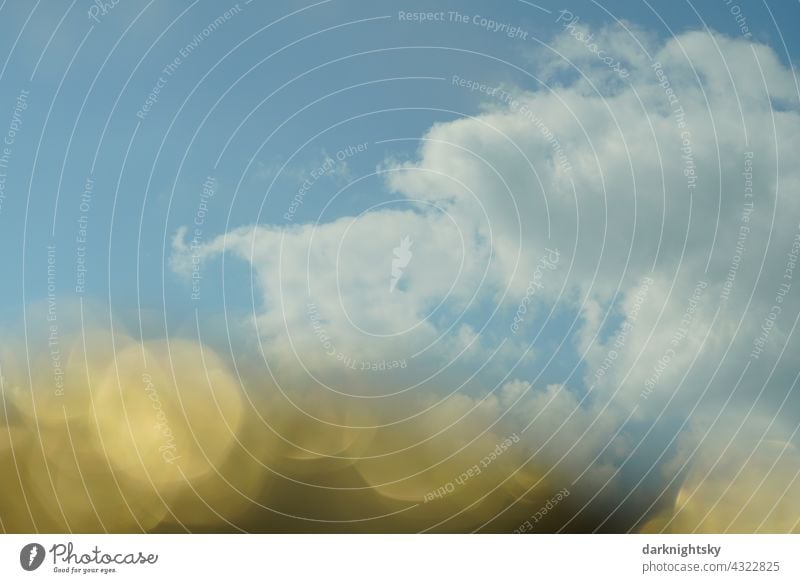 Leicht bis mäßig bedeckter Himmel am späten Abend und bei Gegenlicht durch die Sonne und goldenem Vordergrund mit Bokeh Wolken Licht Unwetter Gewitter