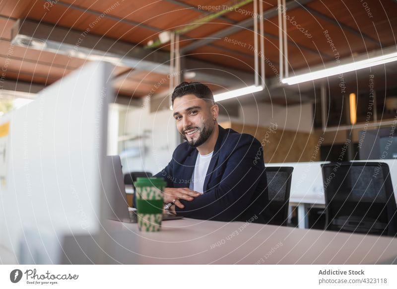 Lächelnder Geschäftsmann am Laptop im Büro Unternehmer Arbeit männlich Arbeitsplatz Arbeitsbereich Business Apparatur benutzend Computer sitzen Netbook Mann