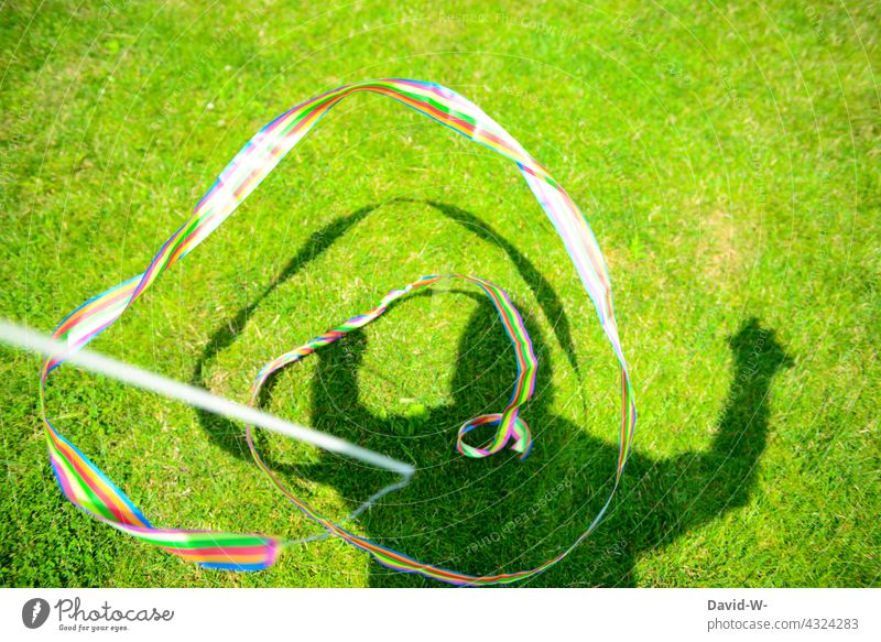 Mann mit buntem Fähnchen - Farbenspiel farbenfroh Hoffnung Lebenslust Vielfältig symbol regenbogenfarben Schatten Harmonie Freude Spaß spielen