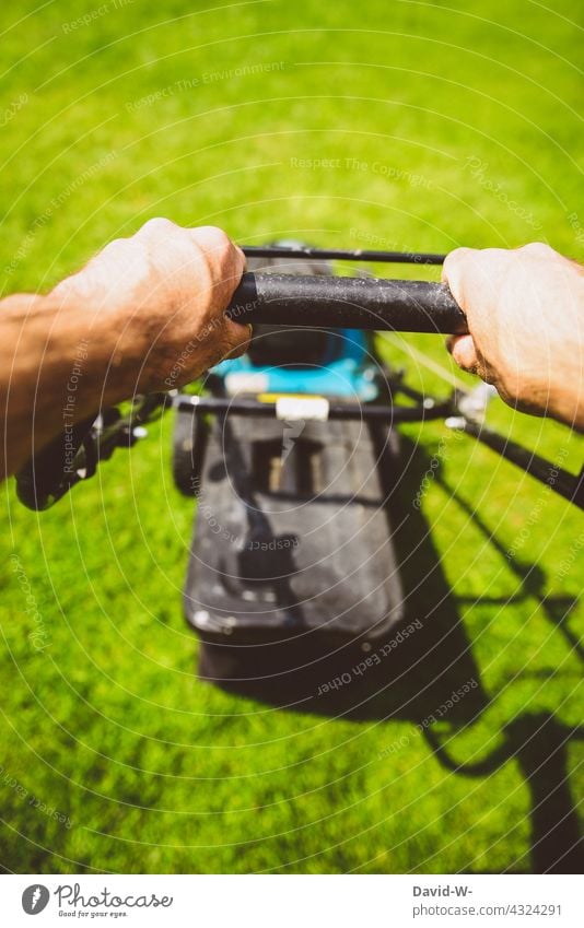 Mann mäht bei Sonnenschein den Rasen mit einem Rasenmäher mähen Hände Gartenarbeit Sommer rasenmähen