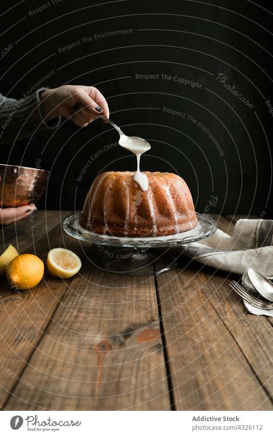 Crop Hand Zuckerguss eine Zitrone Biskuitkuchen Zuckerguß selbstgemacht Dessert Lebensmittel Gebäck Geburtstag lecker gebacken Bäckerei Dame Schürze Pfannkuchen