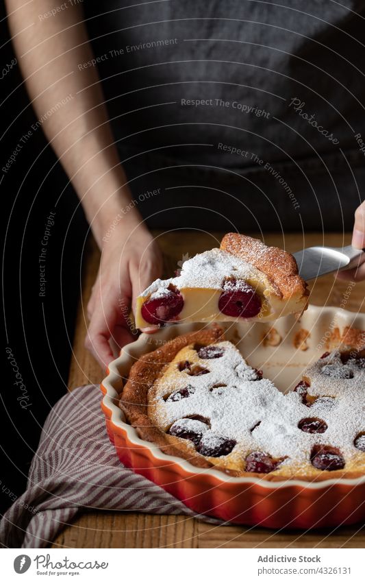 Kropfenkoch mit Stück Kirsch-Clafoutis auf Messer Pasteten Spielfigur Kuchen Koch Person Kirsche geschmackvoll gebacken Gebäck lecker selbstgemacht hölzern