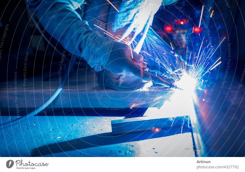 Schweißer schweißt Metall mit Argon-Lichtbogen-Schweißgerät und hat Schweißfunken. Ein Mann trägt Schutzhandschuhe. Sicherheit am industriellen Arbeitsplatz. Schweißer arbeitet mit Sicherheit. Arbeiter in der Stahlindustrie Fabrik.