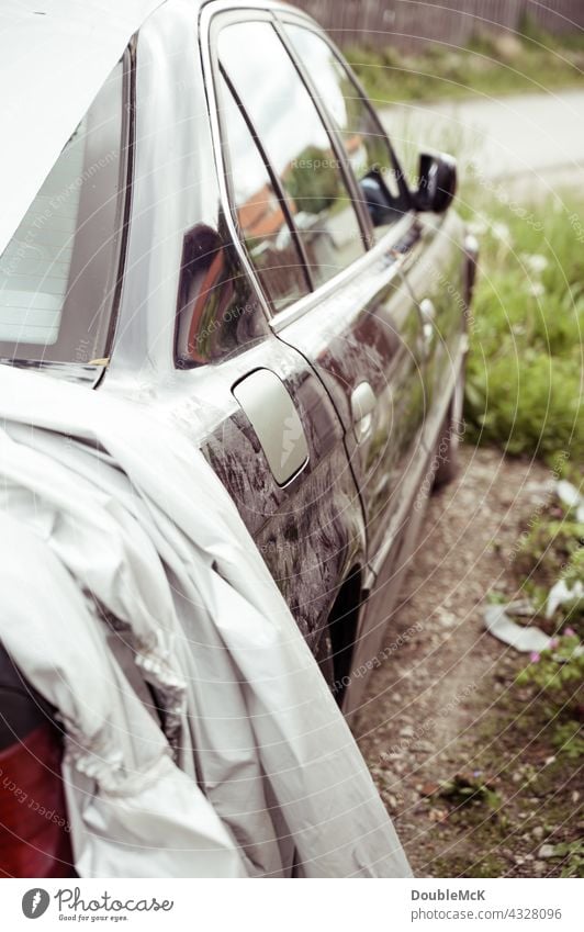 Die rechte Seite eines dreckigen Autos zum Teil mit einer Plane abgedeckt PKW Fahrzeug Verkehrsmittel Straßenverkehr Autofahren Farbfoto Außenaufnahme